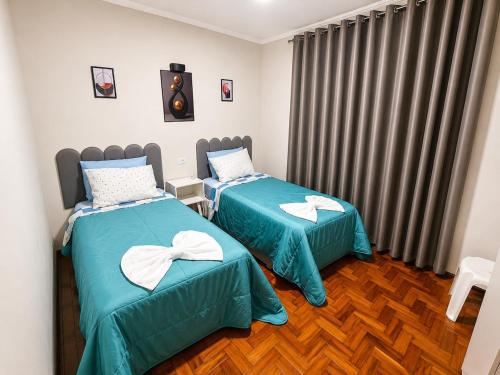 two beds in a room with green sheets at Casa p/ 7 | 3 quartos c/ ar e churrasqueira in Ourinhos