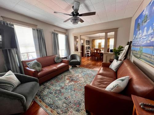 a living room with leather furniture and a ceiling fan at Casa Del Sol Historic St Aug Hideaway in St. Augustine