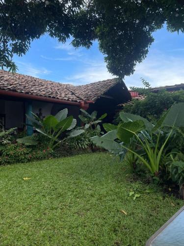 a house with a grass yard next to a building at Hostal Casona de los Vega in Sonsonate
