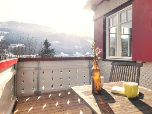 a bottle on a table on a balcony with a window at Daheim Nr 2 - Südwesterhaus Allgäu in Oberstaufen