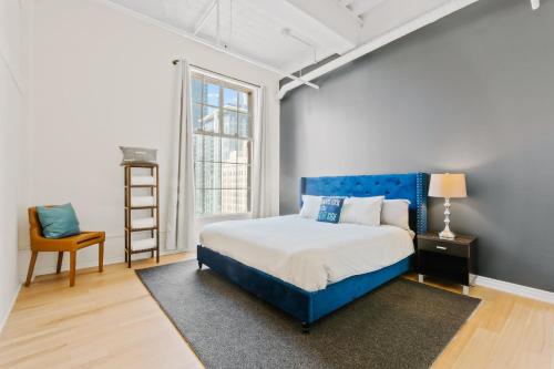 a bedroom with a blue bed and a chair at Rooftop Pool & City Views! Long-Term Dtwn LA Stay in Los Angeles