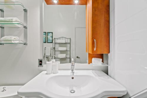 a white bathroom with a sink and a mirror at Rooftop Pool & City Views! Long-Term Dtwn LA Stay in Los Angeles