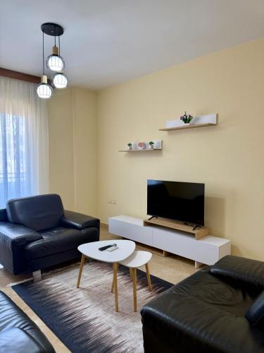 a living room with a couch and a tv and a table at Vlora Center Apartment - 5 Min to Lungomare in Vlorë