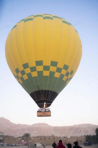 a yellow and green hot air balloon in the sky at Luxor hot air balloon co in Jazīrat al ‘Awwāmīyah