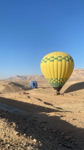 a yellow and green hot air balloon in the desert at Luxor hot air balloon co in Jazīrat al ‘Awwāmīyah