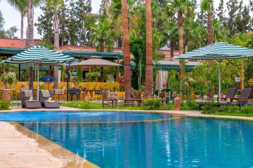 a swimming pool with umbrellas and tables and chairs at Jnane Rihane Marrakech in Marrakesh