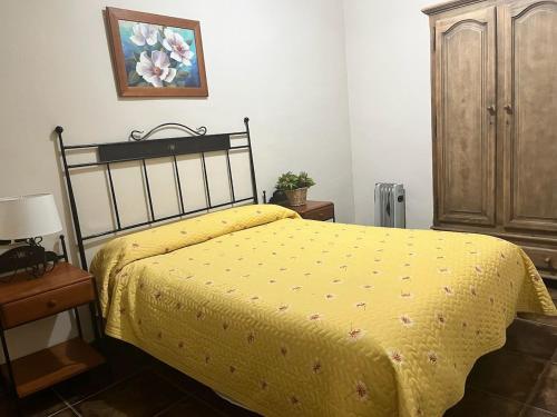 a bedroom with a bed with a yellow bedspread at Apartamentos Esencia vistas embalse 1 in Hornos