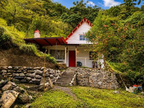 a house with a red door and a stone wall at Cabaña El Cafetal in Valle Hornito