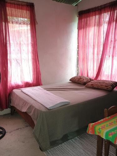 a bedroom with two beds with pink curtains at Casa Rural Los Bufalos - Farm Stay in Guacimo in Guácimo