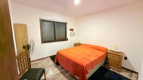 a bedroom with a orange bed and a window at Casitas Atlántida in Atlántida