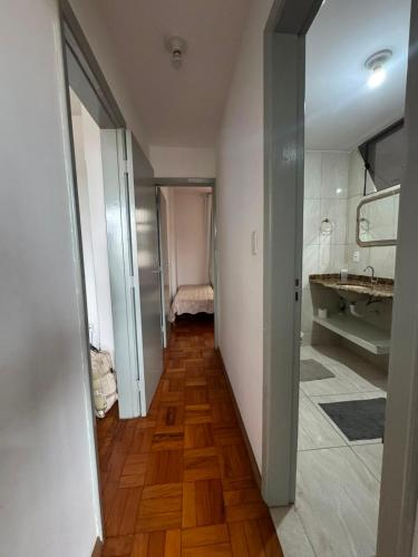 a hallway leading to a bathroom with a sink at Comodidade in Caxambu
