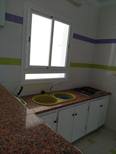 a bathroom with a sink and a window at Résidence R in Ksour Essaf