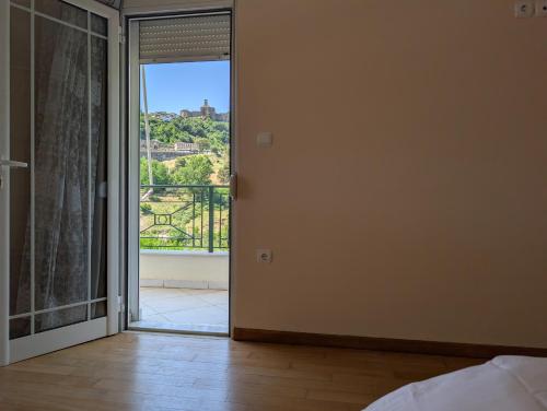 a bedroom with a door open to a balcony at Vila Albert in Gjirokastër