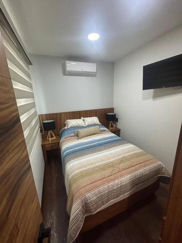 a small bedroom with a bed and a tv at Container Glamping in Zapopan