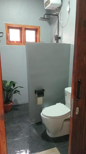 a bathroom with a white toilet and a window at RUMAH BAIQ Villa in Kuta Lombok
