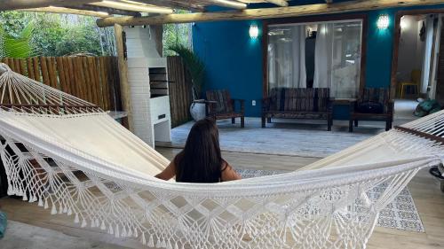 a woman sitting in a hammock in a house at Chalé Paraíso Corumbau - Chalés Uvas Azul in Corumbau