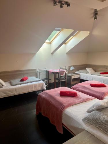 a room with three beds with red sheets and a window at Żywiec CENTRUM Apartamenty z aneksem kuchennym & łazienką in Żywiec