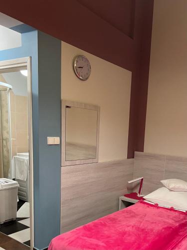 a bedroom with a bed and a clock on the wall at Żywiec CENTRUM Apartamenty z aneksem kuchennym & łazienką in Żywiec