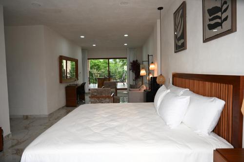 a bedroom with a white bed and a living room at Hotel Casa del Rio in Santiago Tuxtla