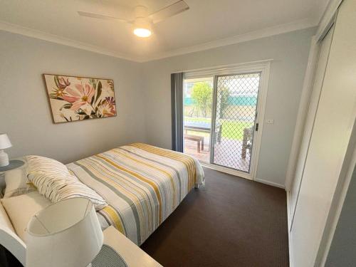 a bedroom with a bed and a sliding glass door at Mountain View Hat Head - Bring your own linen. in Hat Head