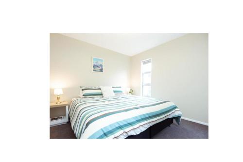 a white bedroom with a bed and a window at Alpine Nook in Methven's Heart, Walk to Town in Methven