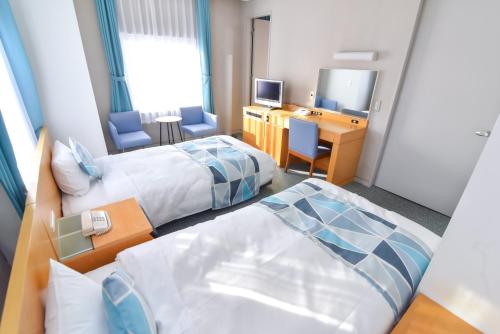 a hotel room with two beds and a desk at Hotel Flex in Hiroshima