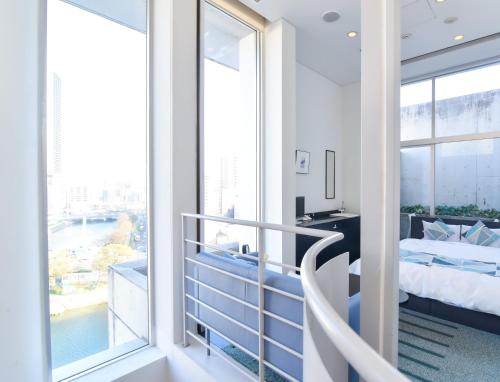 a bedroom with a balcony with a bed and a desk at Hotel Flex in Hiroshima