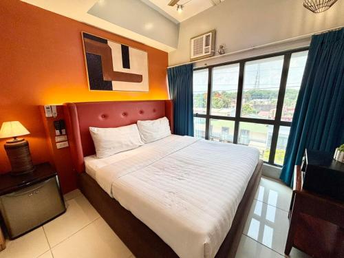 ein Schlafzimmer mit einem großen Bett und einem großen Fenster in der Unterkunft Pacific Park Hotel in Manila