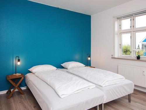 a large white bed in a room with a blue wall at Charming Stay in Ringkobing in Ringkøbing