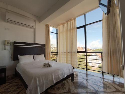 a bedroom with a bed and a large window at Hotel Valle Verde in Tarapoto