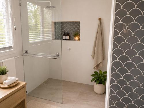 a shower with a glass door in a bathroom at Charming & Spacious 5 Bedroom Bayside House with Pool in Birkdale