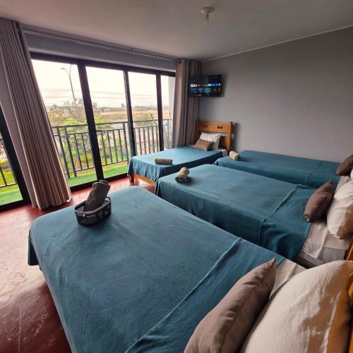 a bedroom with three beds and a balcony at Lima Airport Hostel - FREE AIRPORT PICK UP in Lima