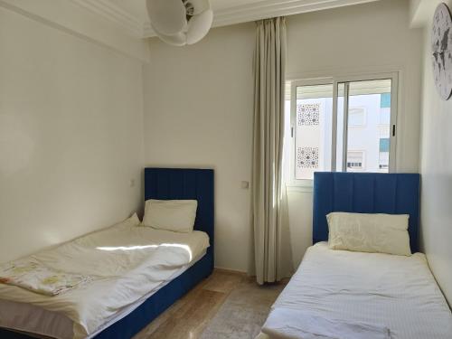 a room with two beds and a window at Cosy appart 3p in Rabat