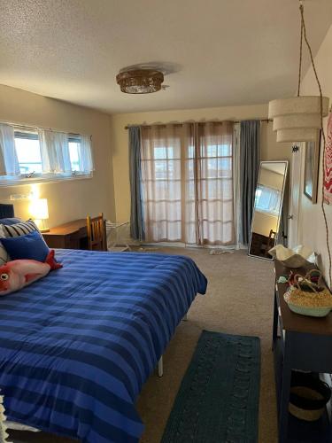 a bedroom with a blue bed and a table and windows at Bluffton Breeze Cottage in Muskegon