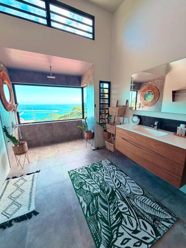 a bathroom with a tub and a sink and a large window at Villa Maeva Tahiti in Vaihi