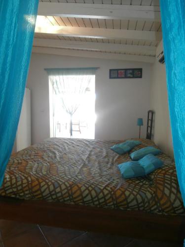 a bedroom with a bed with blue pillows and a window at Villa Alizea in Capesterre-de-Marie-Galante