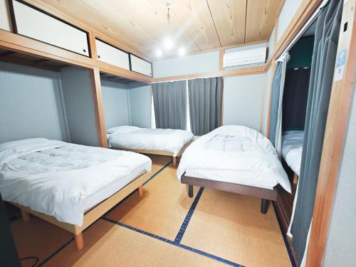 two beds in a small room with windows at 貸切宿ひととき in Numazu