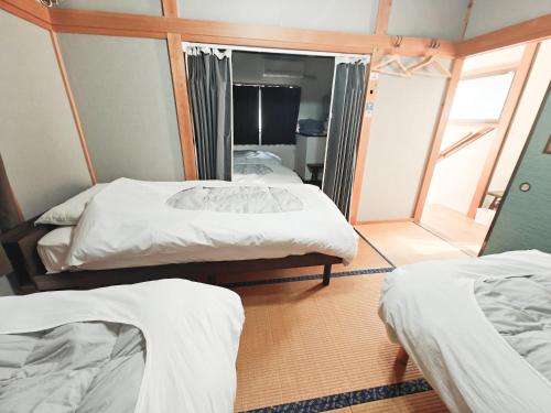two beds in a room with a mirror at 貸切宿ひととき in Numazu