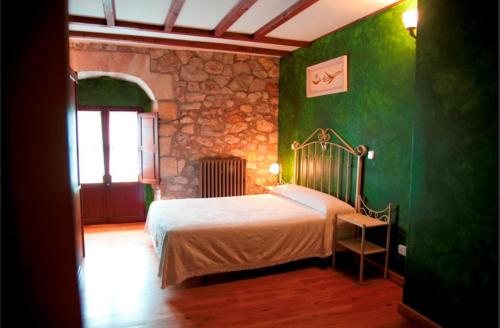 a bedroom with a bed and a stone wall at Posada El Pozo in Castanedo
