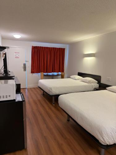 a hotel room with two beds and a window at Coastline Motel Kamloops in Kamloops