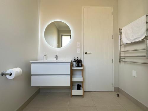 a white bathroom with a sink and a mirror at Sweet Serendipity in Tauranga