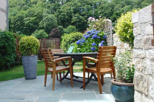 a patio with a table and chairs and flowers at La Sabotiere in Plumeliau Bieuzy