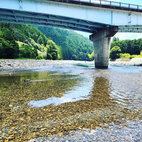 a bridge over a river with rocks and water at SEN RETREAT CHIKATSUYU - Kumano Kodo Gateway in Tanabe