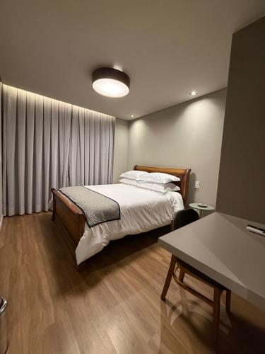 a bedroom with a bed and a table at Apartamento 204 Cheia de Graca in Divinópolis