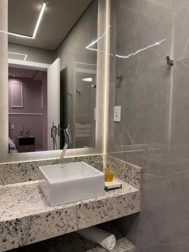 a bathroom with a sink and a mirror at Apartamento 204 Cheia de Graca in Divinópolis