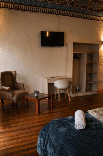 a room with a bed and a chair and a television at Suite Colonial Patrimonio UNESCO Centro Histórico Cuenca in Cuenca