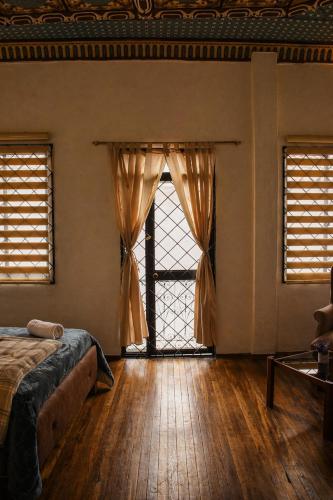 a bedroom with a bed and a large window at Suite Colonial Patrimonio UNESCO Centro Histórico Cuenca in Cuenca