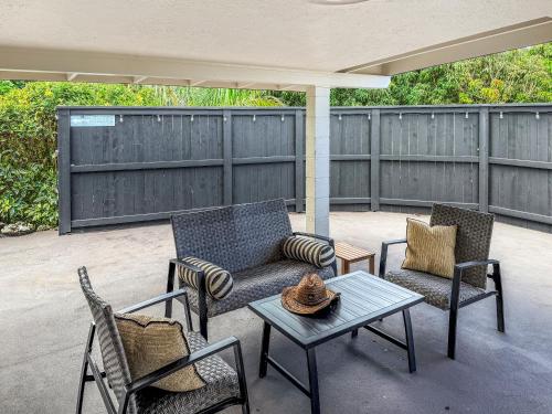 a patio with two chairs and a table and a couch at Coral Wave Cottage in Waialua