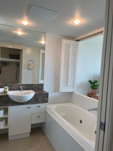 a bathroom with a tub and a sink and a bath tub at Broadbeach on the Park in Gold Coast