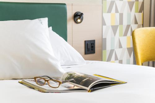 a book and a pair of glasses on a bed at ANA Holiday Inn Kobe Sanda by IHG in Sanda